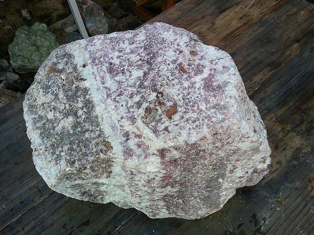Vue du bloc de lépidolite brut présentant un contraste entre violet profond, ligne blanche et zone grisée.