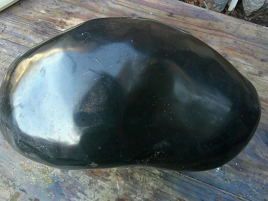 Masse de tourmaline polie révélant les nuances internes du minéral - bloc naturel en attente de sculpture.