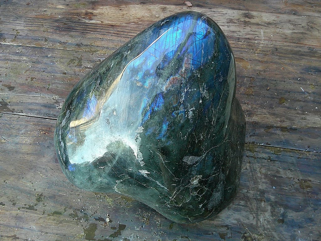 Labradorite polie de Madagascar montrant ses jeux de lumière bleus caractéristiques, bloc brut en attente de sculpture.