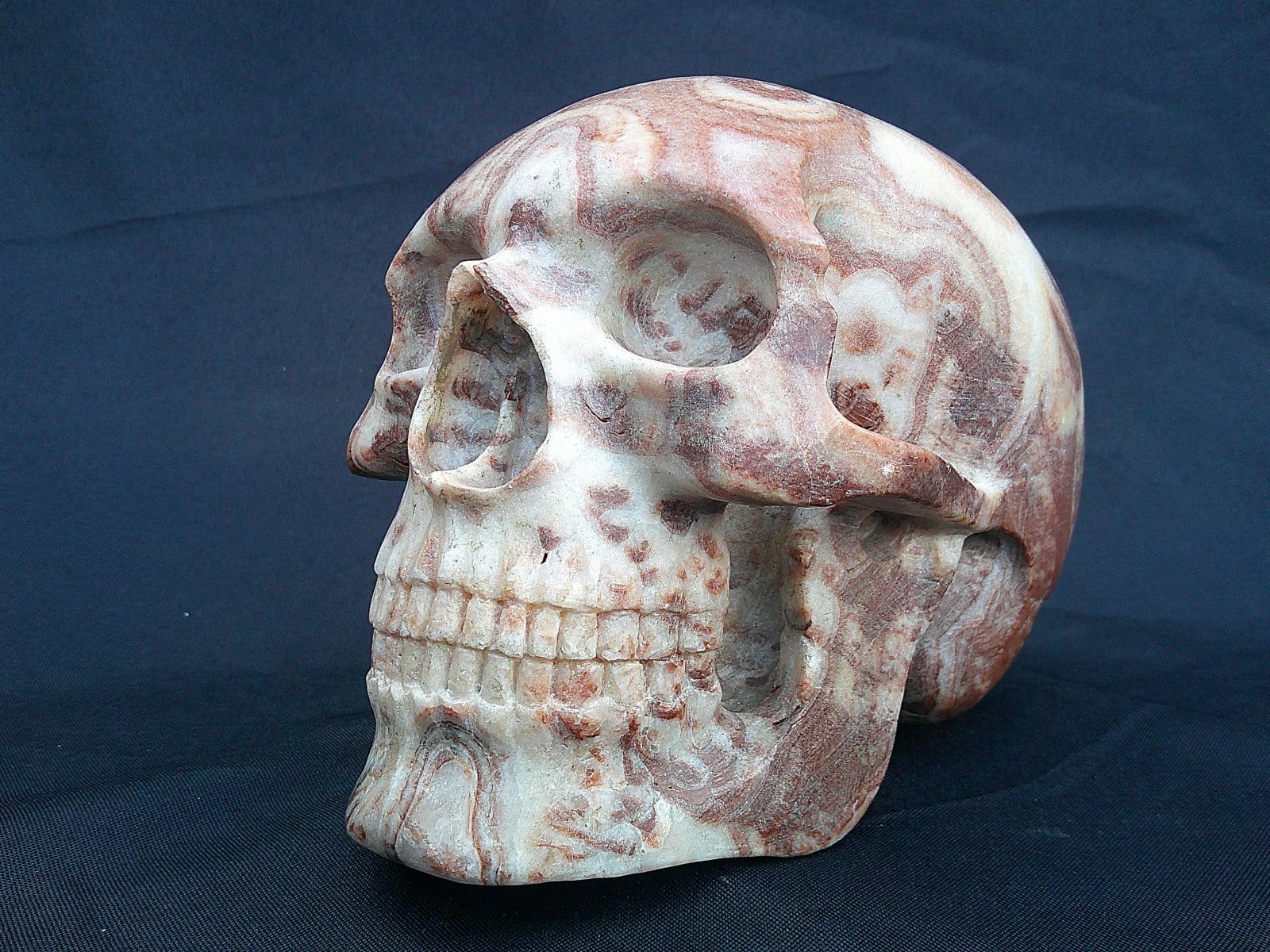 Crâne “La Madre” sculpté dans une stalagmite d’aragonite de l’Hérault, montrant les veines naturelles du minéral.