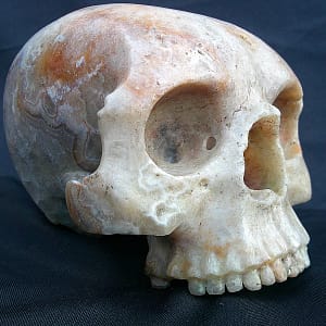Sculpture “Le Caverneux”, crâne sans mandibule taillé dans une agate de la Dourbie, montrant les cavités naturelles du minéral.
