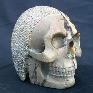 Perspective latérale de “Le Guerrier”, crâne sculpté dans une septaria de Madagascar avec arrière travaillé en motif de côte de maille.