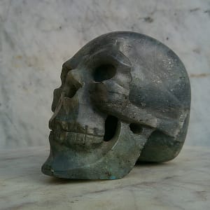 Crâne sculpté en labradorite, vue de profil gauche, sculpture en pierre naturelle taillée et polie à la main.