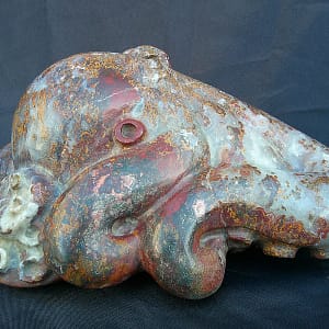 Perspective latérale de la sculpture “Kraken”, pieuvre en agate rouge dévoilant la finesse du travail sur les tentacules.