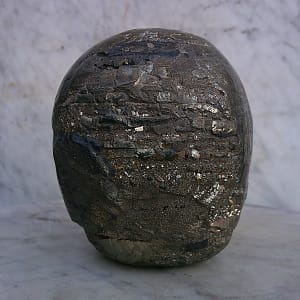 Sculpture de crâne humain en pyrite, vue arrière, pièce unique sculptée à la main dans un bloc de minéral naturel, montrant la surface postérieure du crâne, la structure cristalline apparente de la pyrite, les zones plus brutes et les traces du travail de taille réalisées à l’atelier.