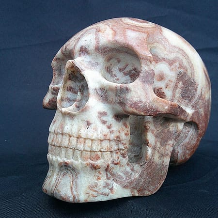 Crâne “La Madre” sculpté dans une stalagmite d’aragonite de l’Hérault, montrant les veines naturelles du minéral.