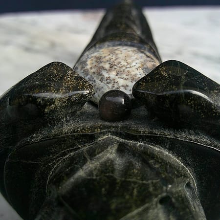 Détail de la perle d’obsidienne montée sur le poignard “La Griffe du Dragon”, avec texture brillante et reliefs sculptés.